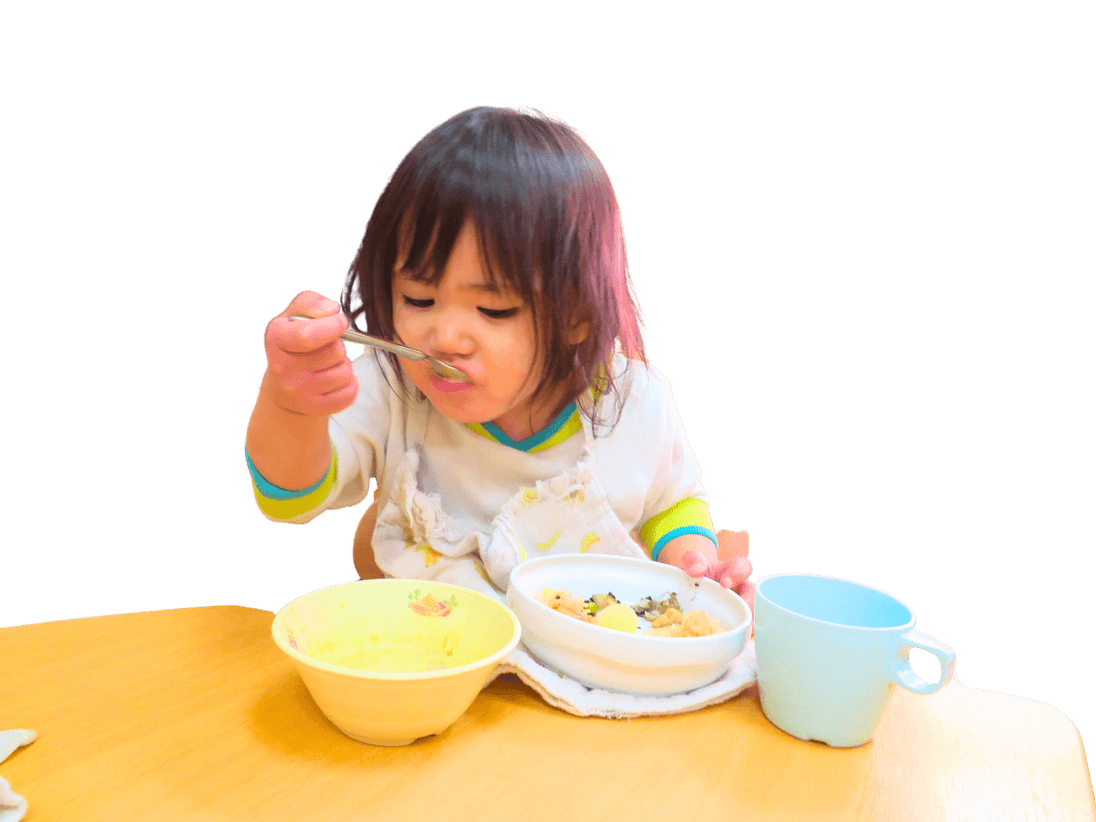 スプーンで給食を楽しむ園児