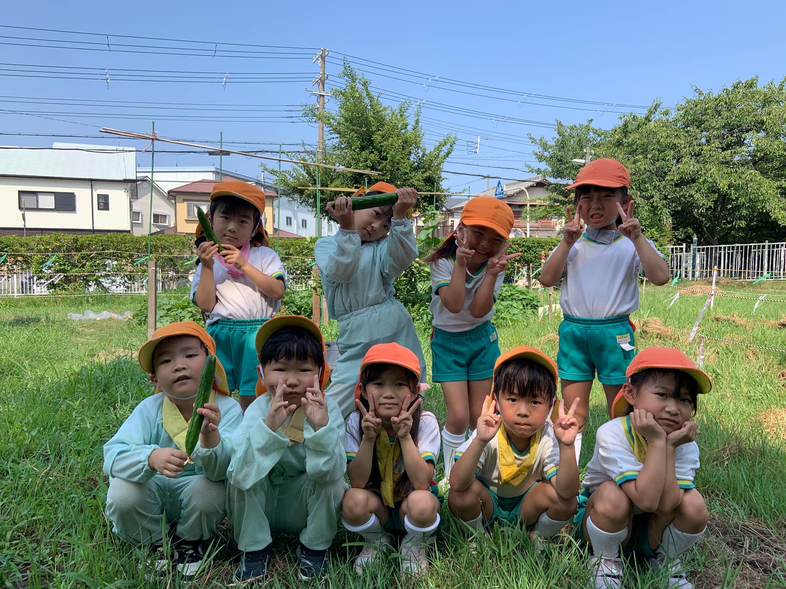 園の畑で収穫したきゅうりを手にする園児たち