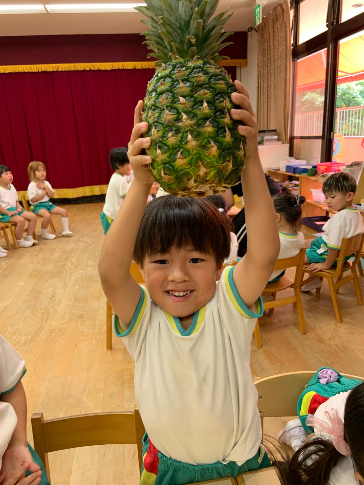大きなパイナップルを持ち上げる園児