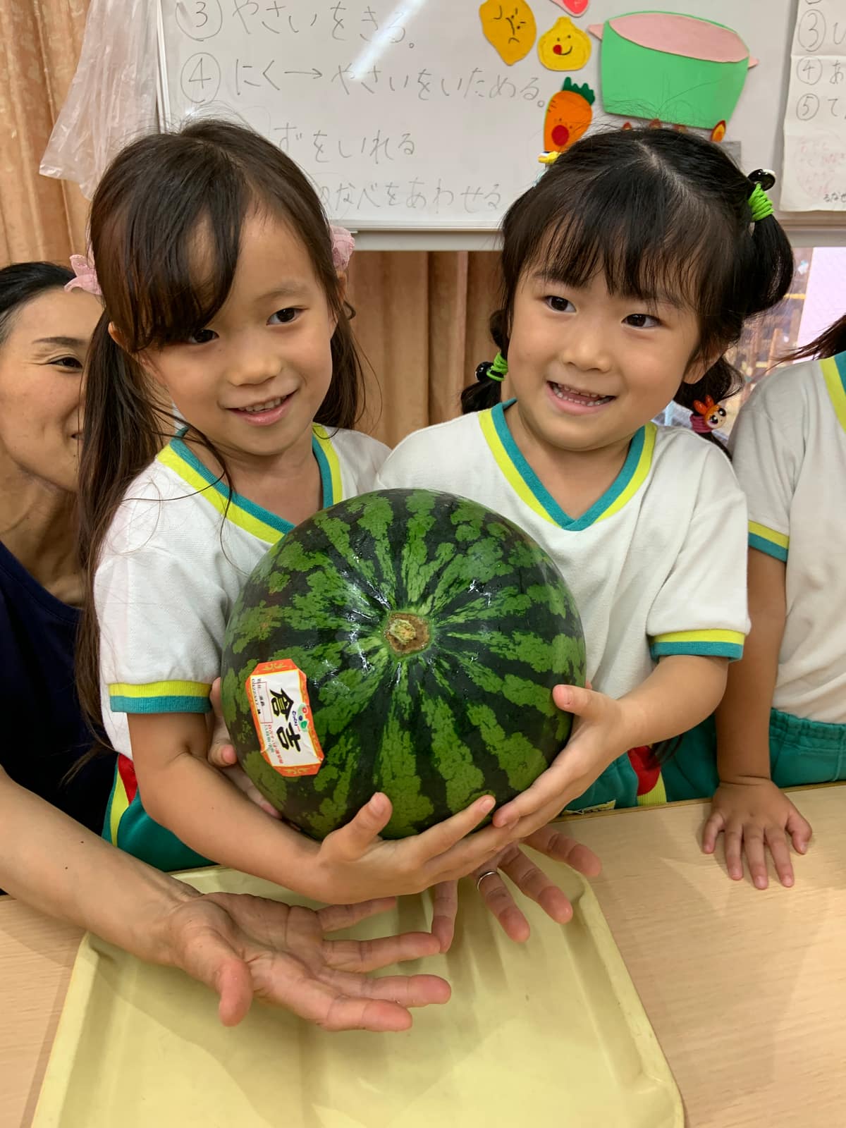 大きなすいかを一緒に抱える園児たち