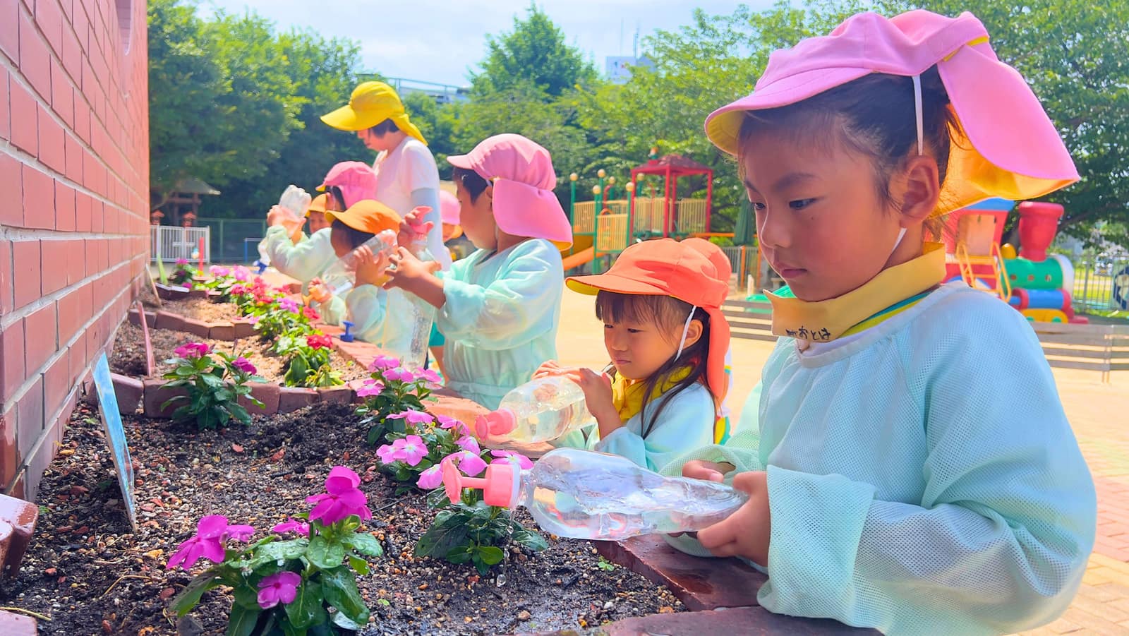 園庭の花に水をあげる園児たち