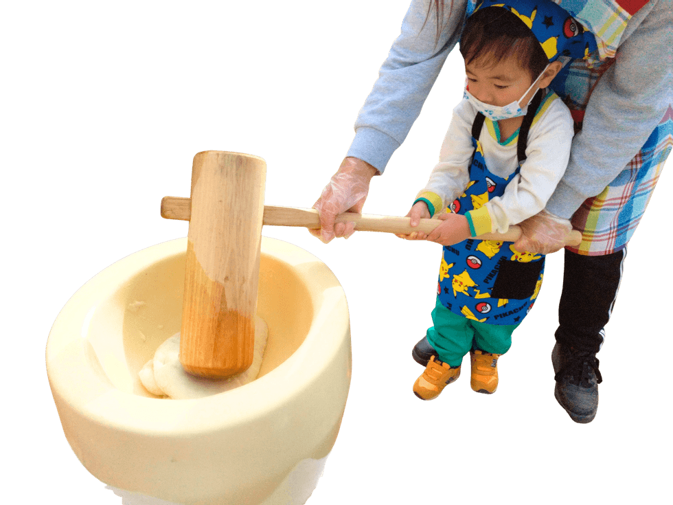 先生と一緒にもちつきを体験する園児